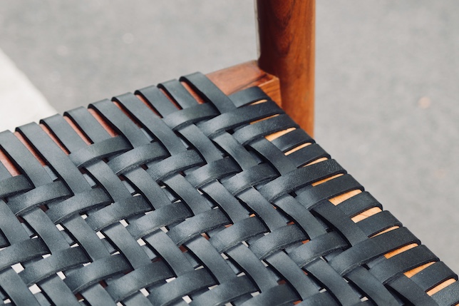 Detailansicht eines mit schwarzen Lederriemen im Köpermuster bespannten Designerstuhls